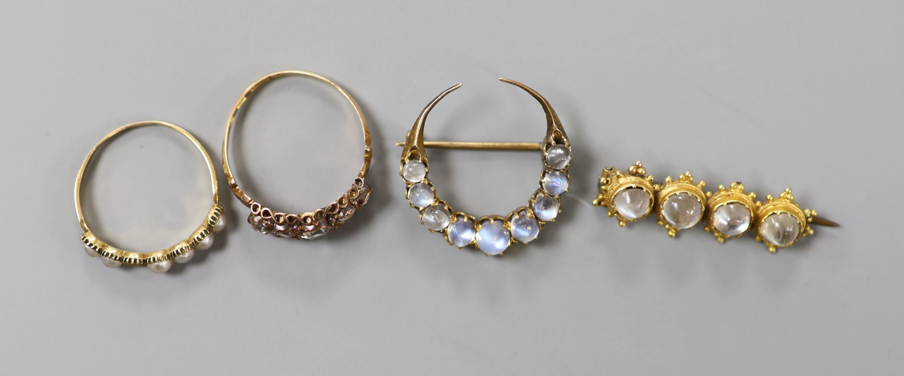A Victorian 15ct gold and graduated aquamarine set half hoop ring, size O, gross 1.8 grams, a split pearl set ring(a.f.) and two antique yellow metal and moonstone set brooches, including crescent, gross 6.4 grams.